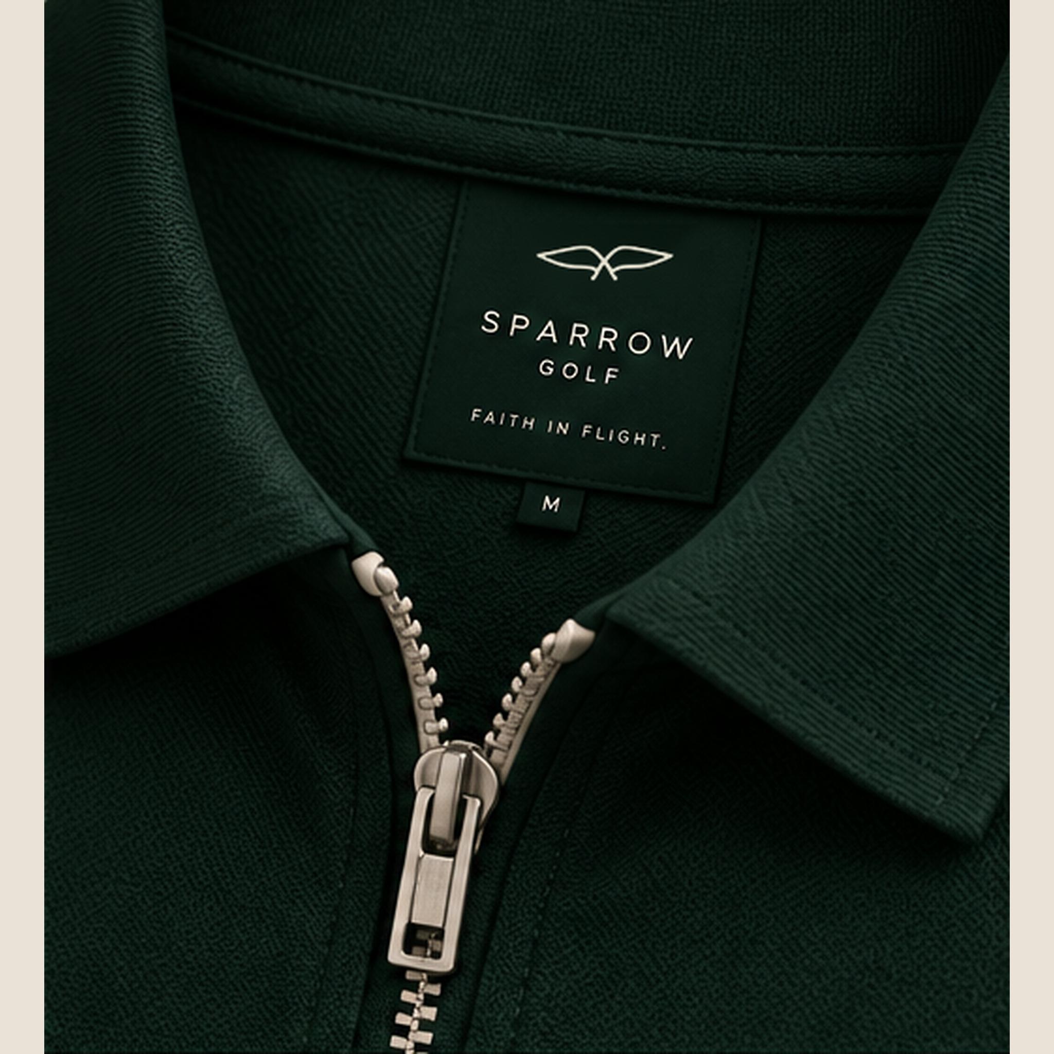 Woven neck label reading Sparrow Golf, Faith in Flight, above a metal zip.